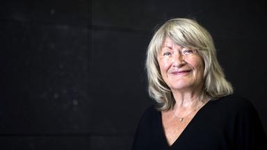 Eine ältere Frau mit schulterlangen grauen Haaren lächelt in die Kamera.