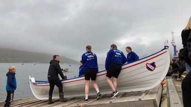 Färöer Jugendliche lassen ihr Boot ins Wasser.