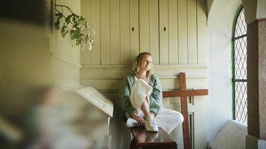 Anne sitzt neben der Orgel am Fenster.