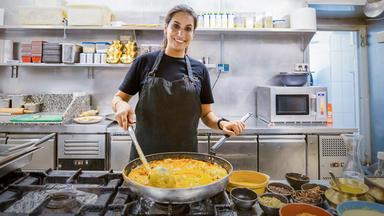 Eine junge Frau in einer Industrieküche.