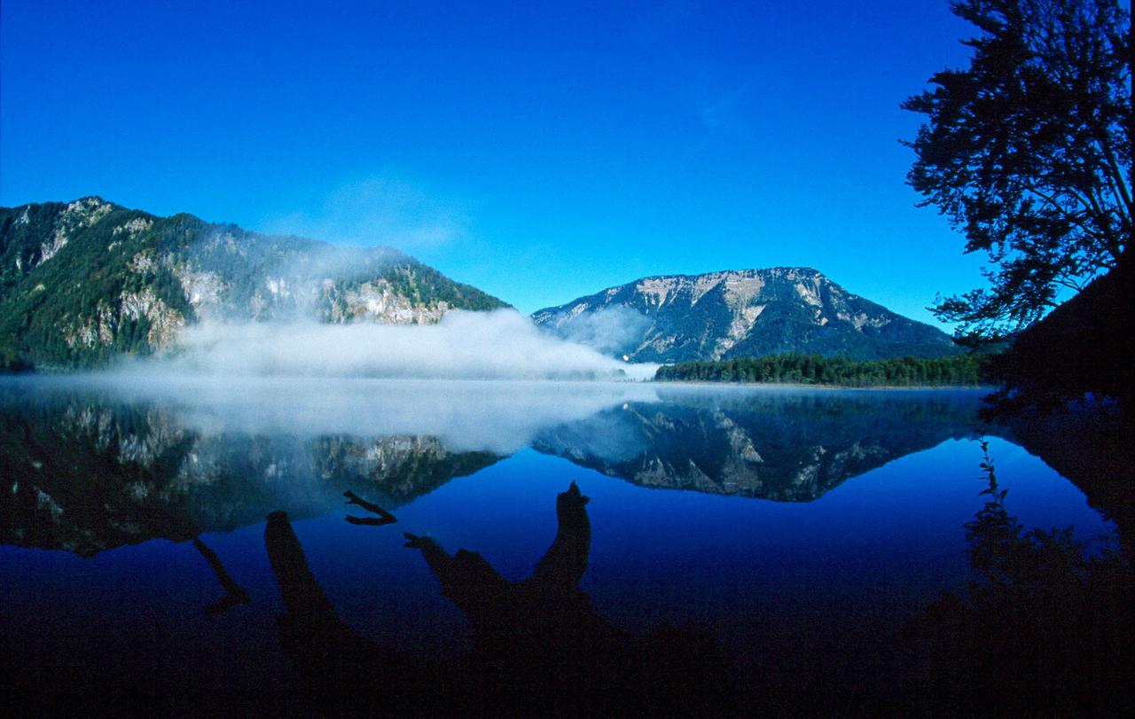 Berge spiegeln sich in dem Wasser eines Alpensees