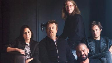 Die Bandmitglieder vor dunklem Hintergrund