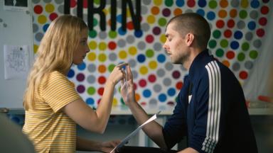 Ein Mann und eine Frau sitzen sich gegenüber und berühren sich an der Hand.