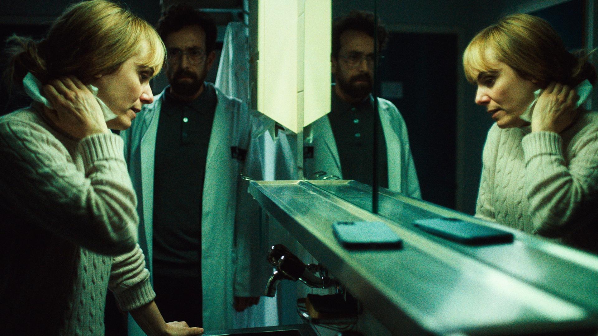 Anna Pieri Zuercher als Camille Aubry und Luca Di Giovanni als Kurt Lengen in einem aufgeladenen Gespräch in einem Innenraum.