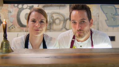 Eine Frau und ein Mann hinter einer Anreiche.