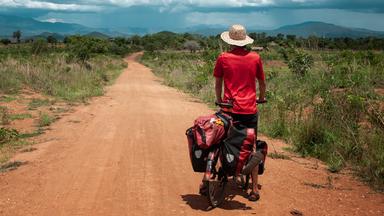 Anselm Nathanael Pahnke von hinten auf Fahrrad. Er blickt in die Landschaft.