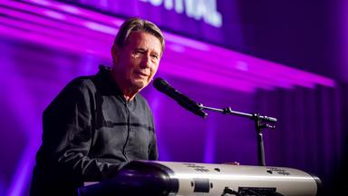 Andreas Rebers sitzt am Piano und blickt in die Kamera. Der Hintergrund ist lila.