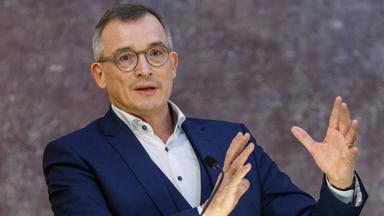 Mann gestikuliert beim Sprechen an einem Rednerpult