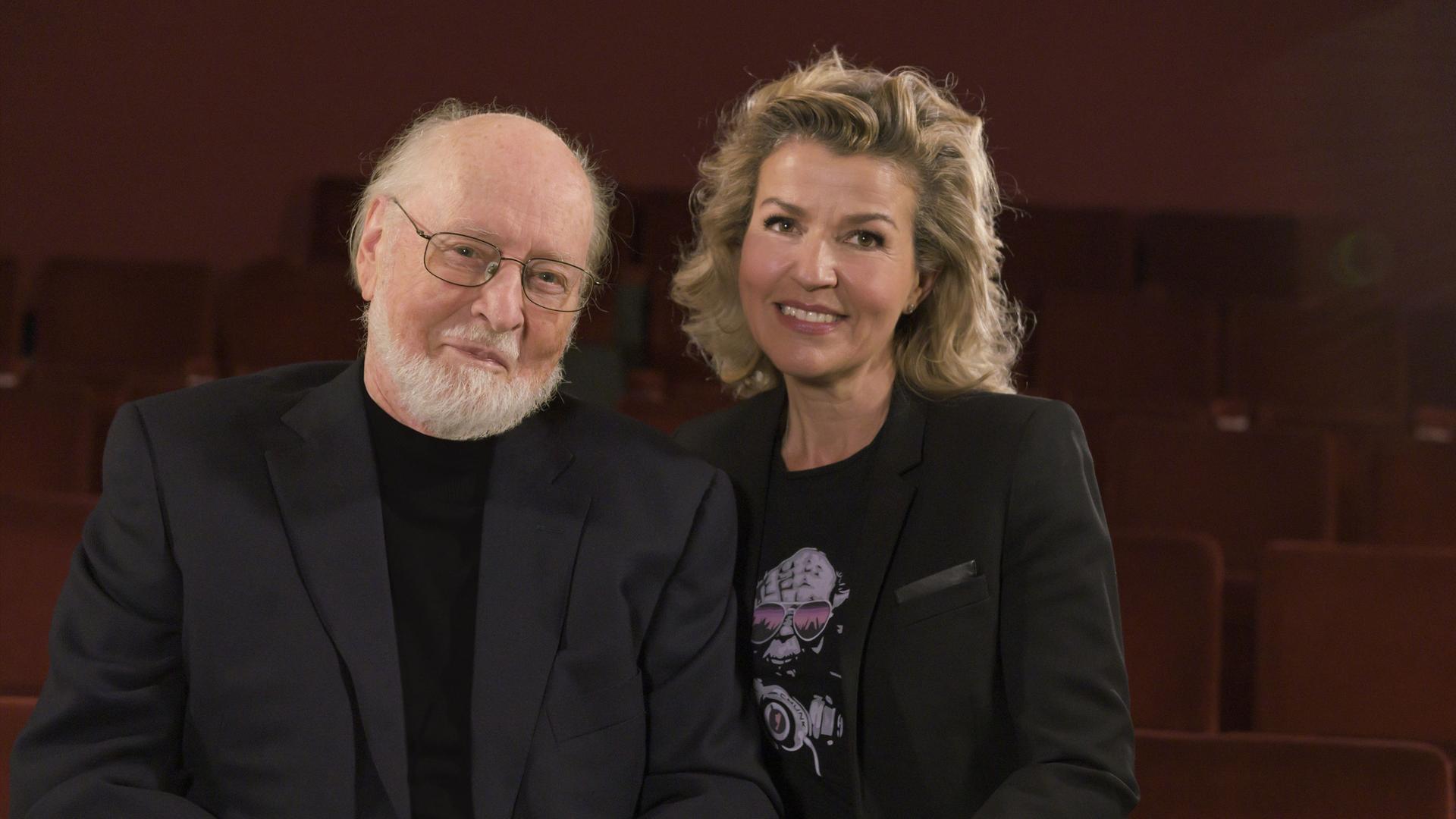 John Williams (re)und Anne-Sophie Mutter (re) stehen zusammen und lächeln. 
