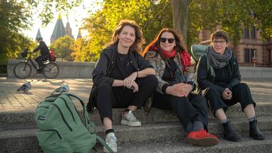 Schriftstellerinnen Peggy Mädler, Annett Gröschner (Mainzer Stadtschreiberin) und Wenke Seemann (von links nach rechts) sitzen auf der Rheintreppe in Mainz. 