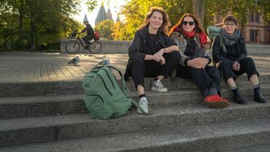Schriftstellerinnen Peggy Mädler, Annett Gröschner (Mainzer Stadtschreiberin) und Wenke Seemann (von links nach rechts) sitzen auf der Rheintreppe in Mainz. 