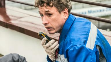 Ein Mann blickt besorgt neben die Kamera und spricht in ein Funkgerät.