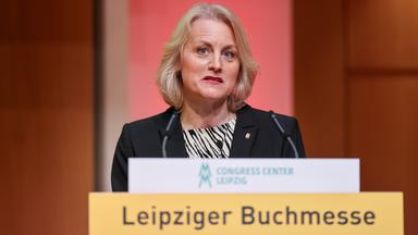 Dame läuft an Säulengang entlang.