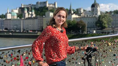 Moderatorin Tamina Kallert ist mit ihrem Rad auf einer Brücke, an der viele Schlösser hängen.