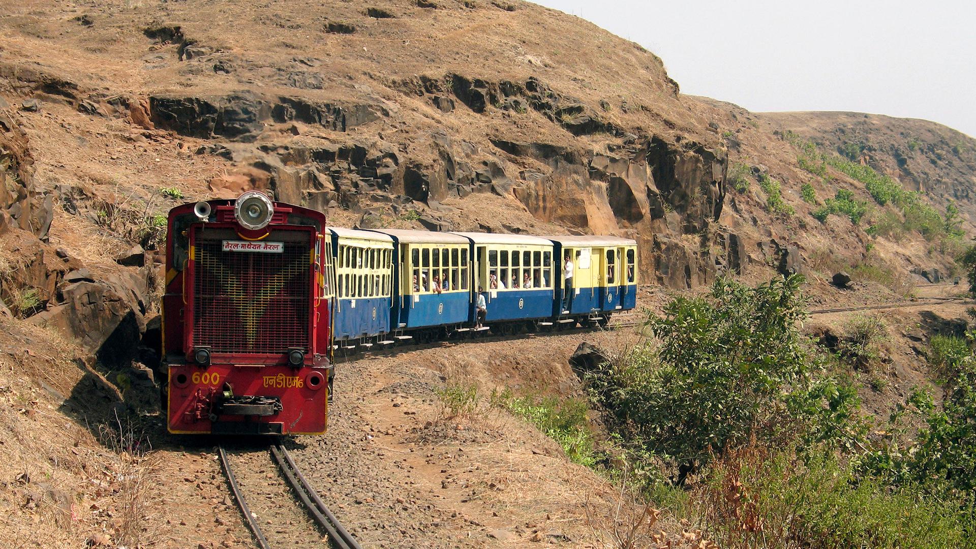 Ein blau-roter Zug an einem Berghang.