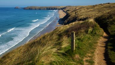 Ein Wanderweg entlang der Küste mit Blick auf blaues Meer und Felsen