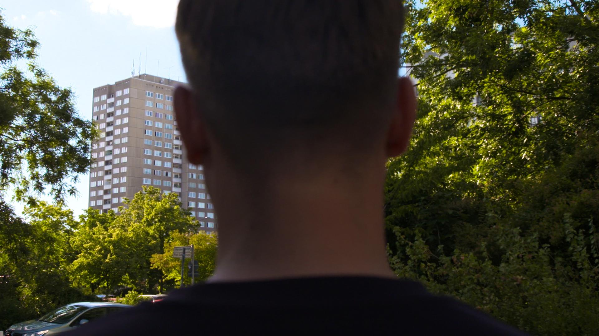 männlicher Hinterkopf vor Hochhaus.