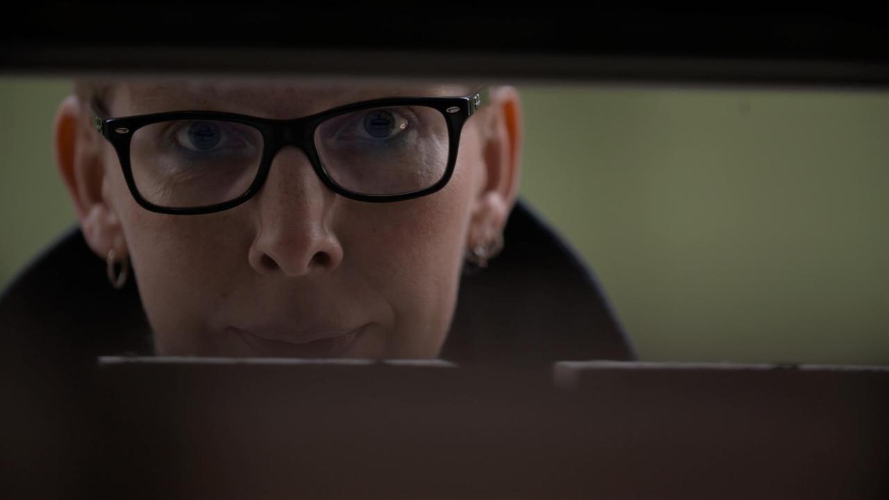 Frau mit Brille guckt durch zwei Balken durch