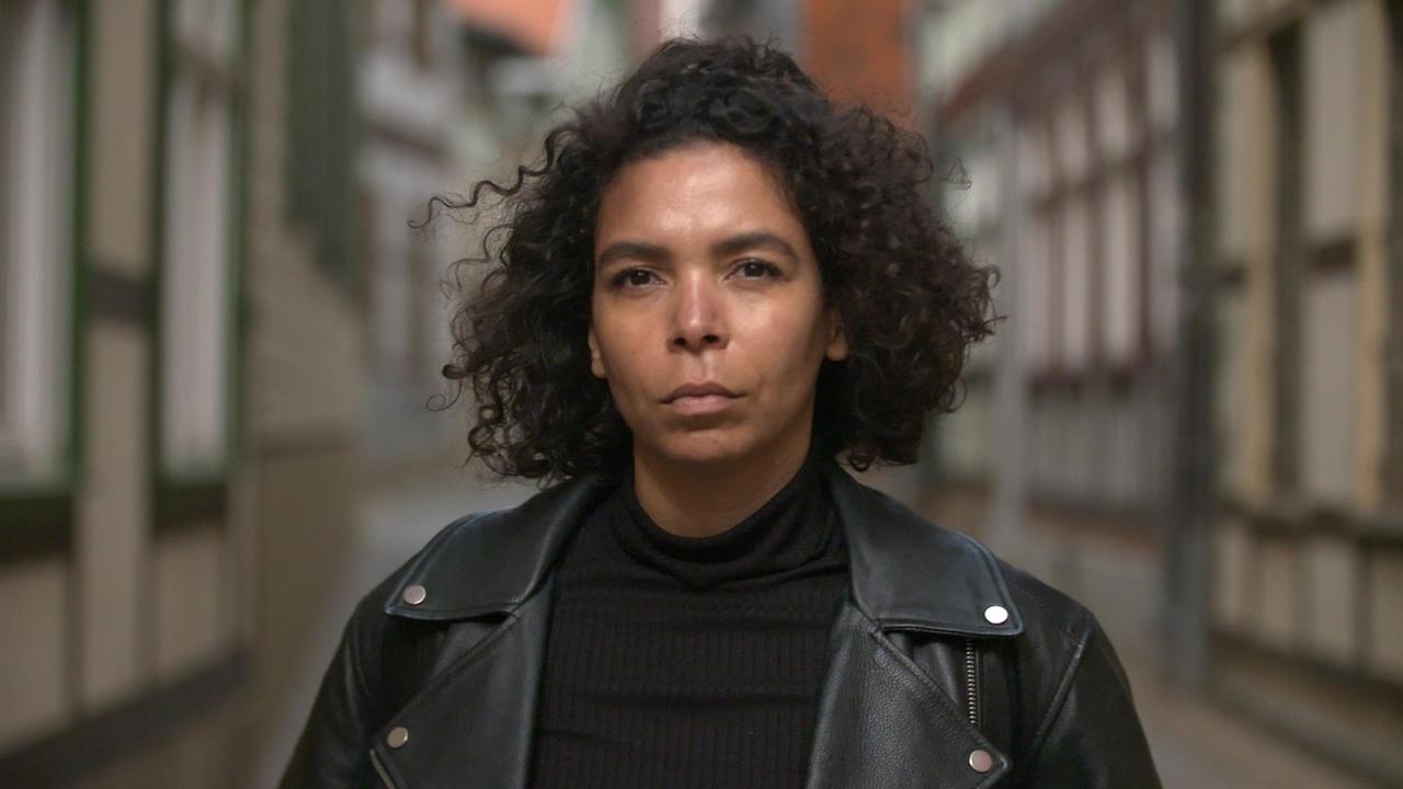 dunkelhäutige, junge Frau vor Fachwerk-Fassade