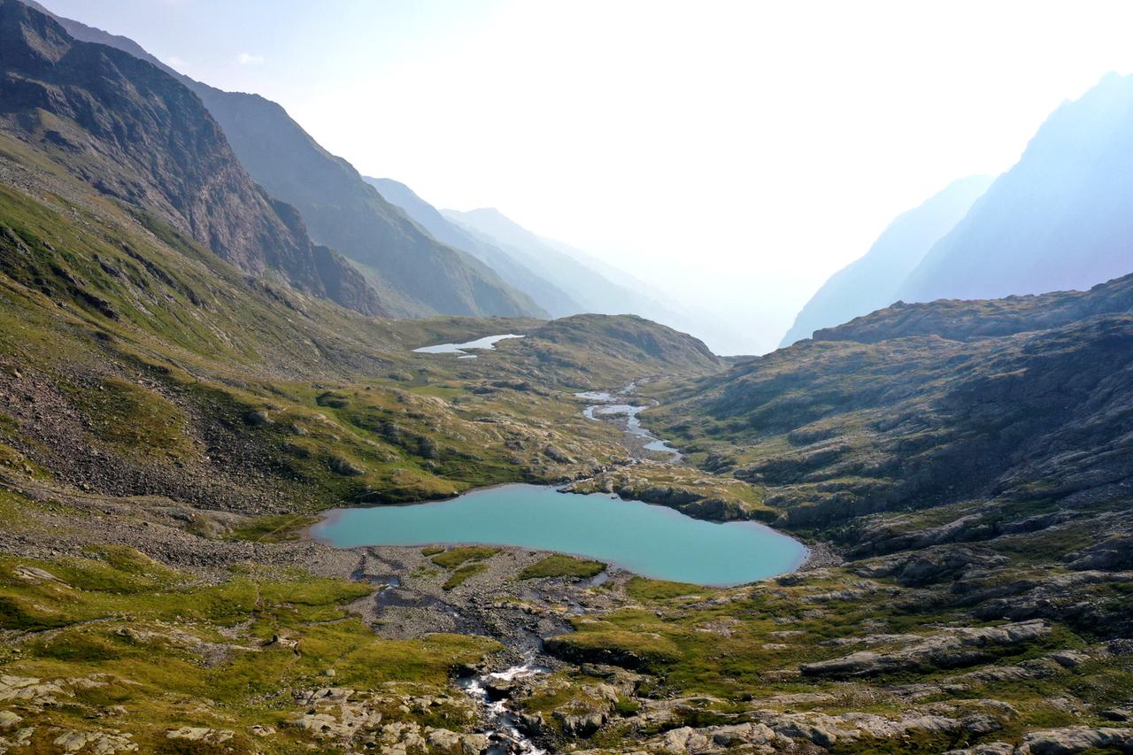 Kleiner Bergsee mit vernebeltem Talblick