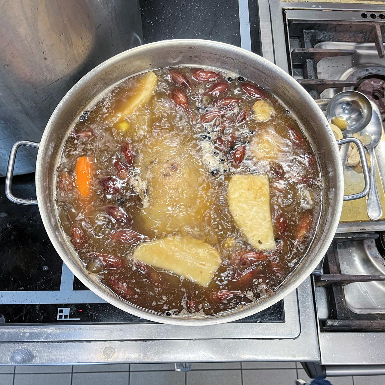 Blick von oben auf sprudelnd kochende Suppe mit Gemüse