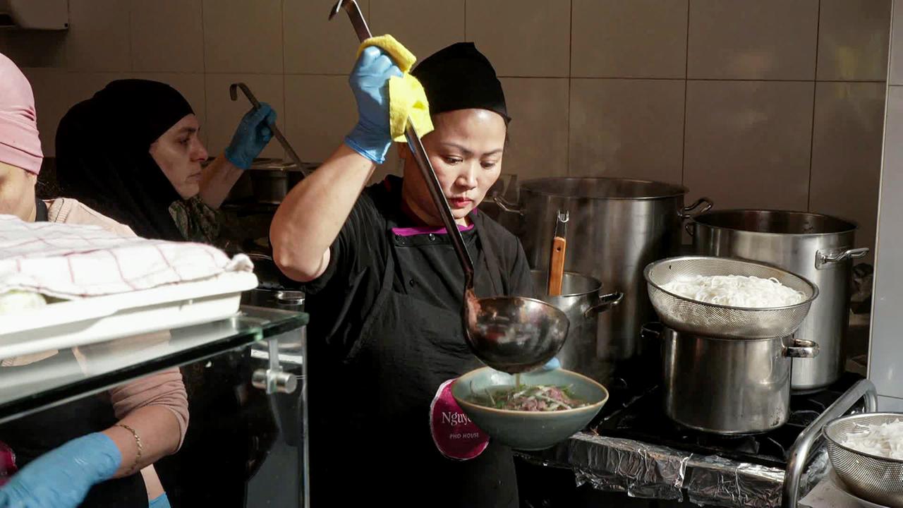 Asiatische Köchin füllt Suppe mit großer Kelle in eine Schale