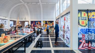 In einem Ausstellungsraum stehen Schaukästen. Menschen schauen sich die Exponate an.