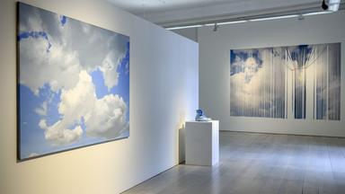 In einem Ausstellungsraum sieht man Exponate mit Wolkenmotiven.