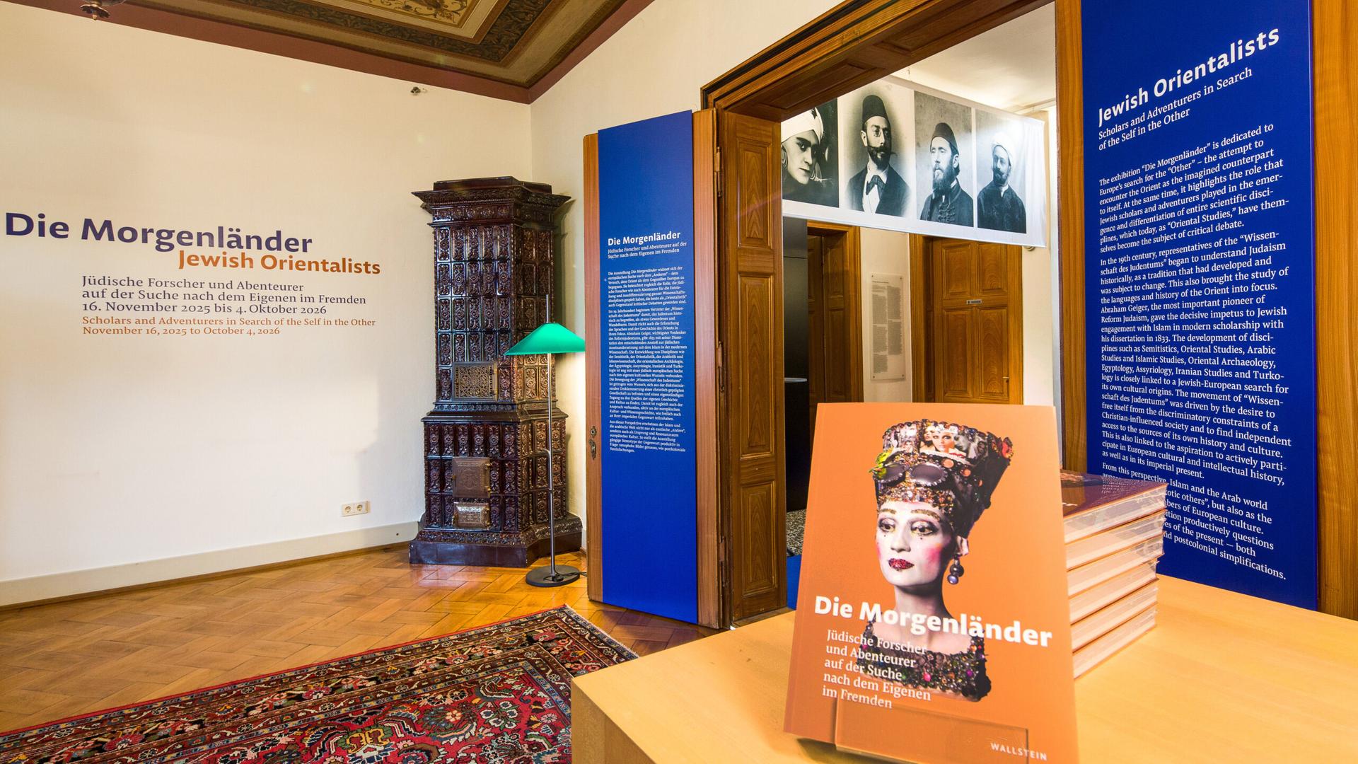 In einem Ausstellungsraum stehen Exponate und hängen Bilder von Personen an der Wand.