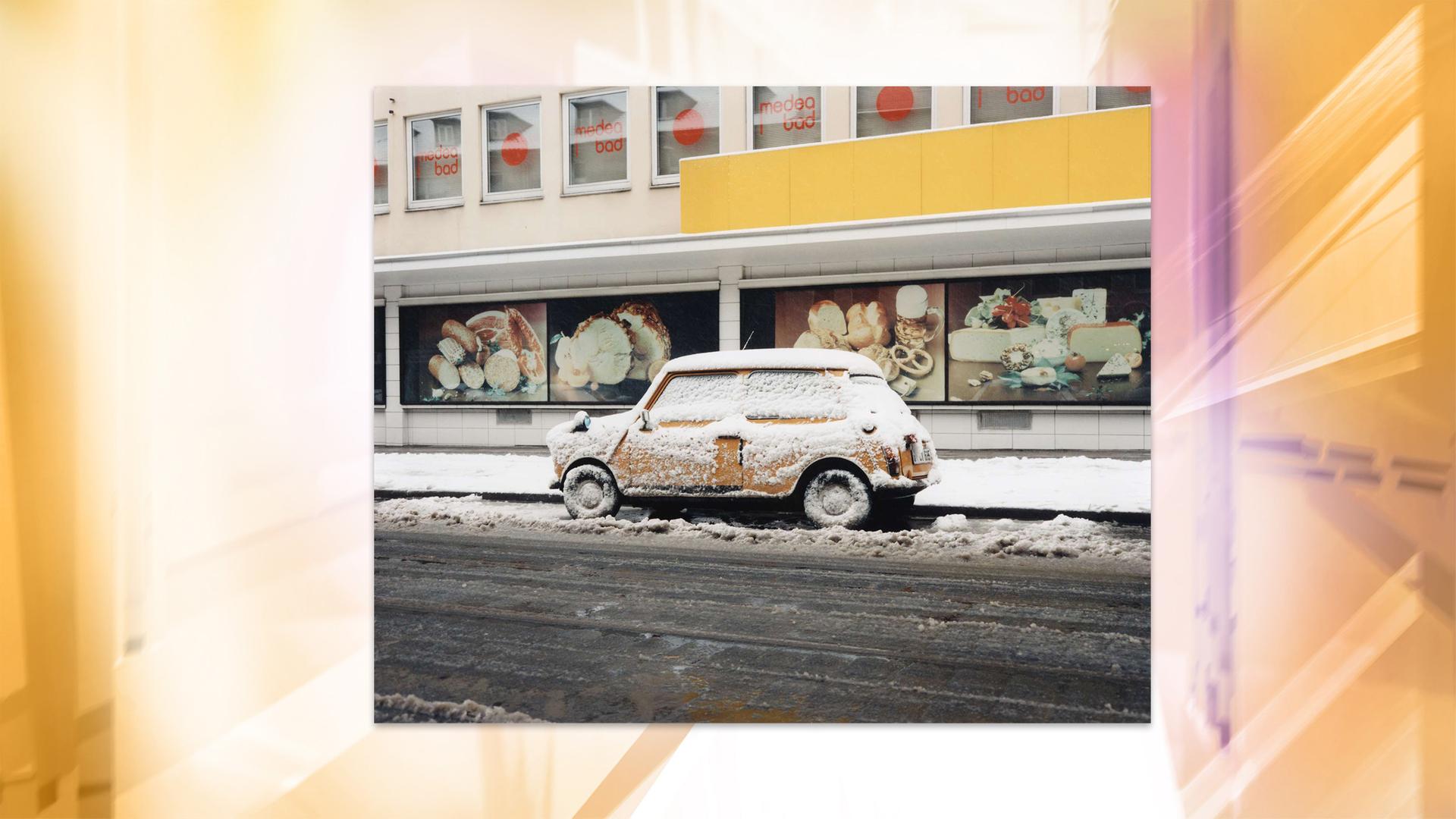 Ein verschneites Auto ist vor einem Geschäft geparkt.