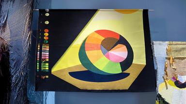 Man sieht die Installation eines modernen, bunten Kunstwerkes in einem Ausstellungsraum.