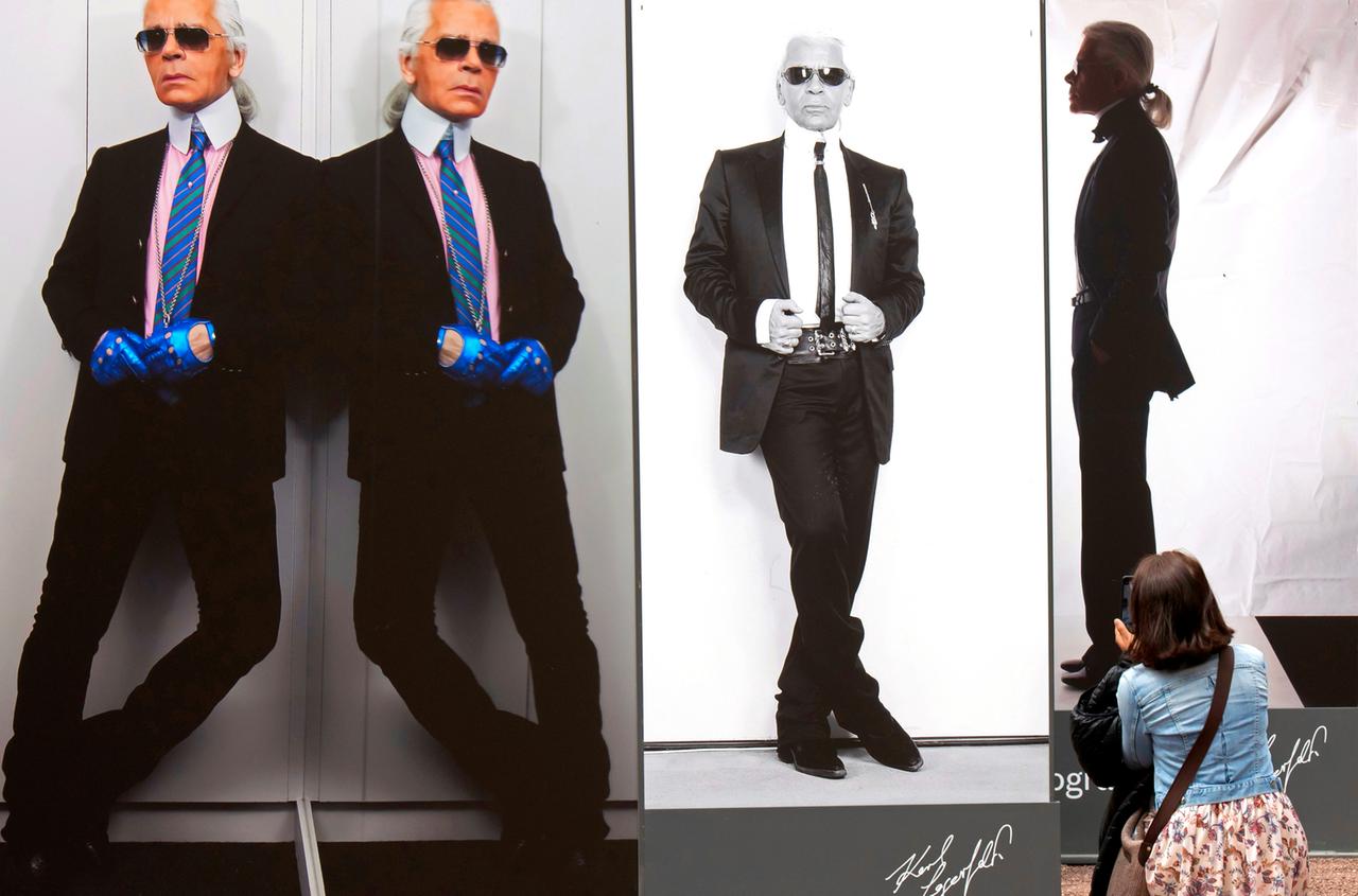 Nebeneinander gestellte überlebensgroße Fotos des Designers Karl Lagerfeld zeigen einen Mann im Anzug, Hemd mit Vatermörder-Kragen, Krawatte, dunkler Sonnenbrille und Zopf.