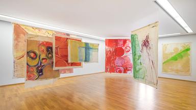 In einem Ausstellungsraum sind bunte, moderne Kunstwerke ausgestellt.