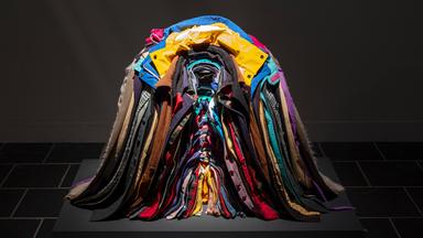 Zu sehen ist ein bunter, ordentlich ineinander gestapelter Haufen aus Jacken.