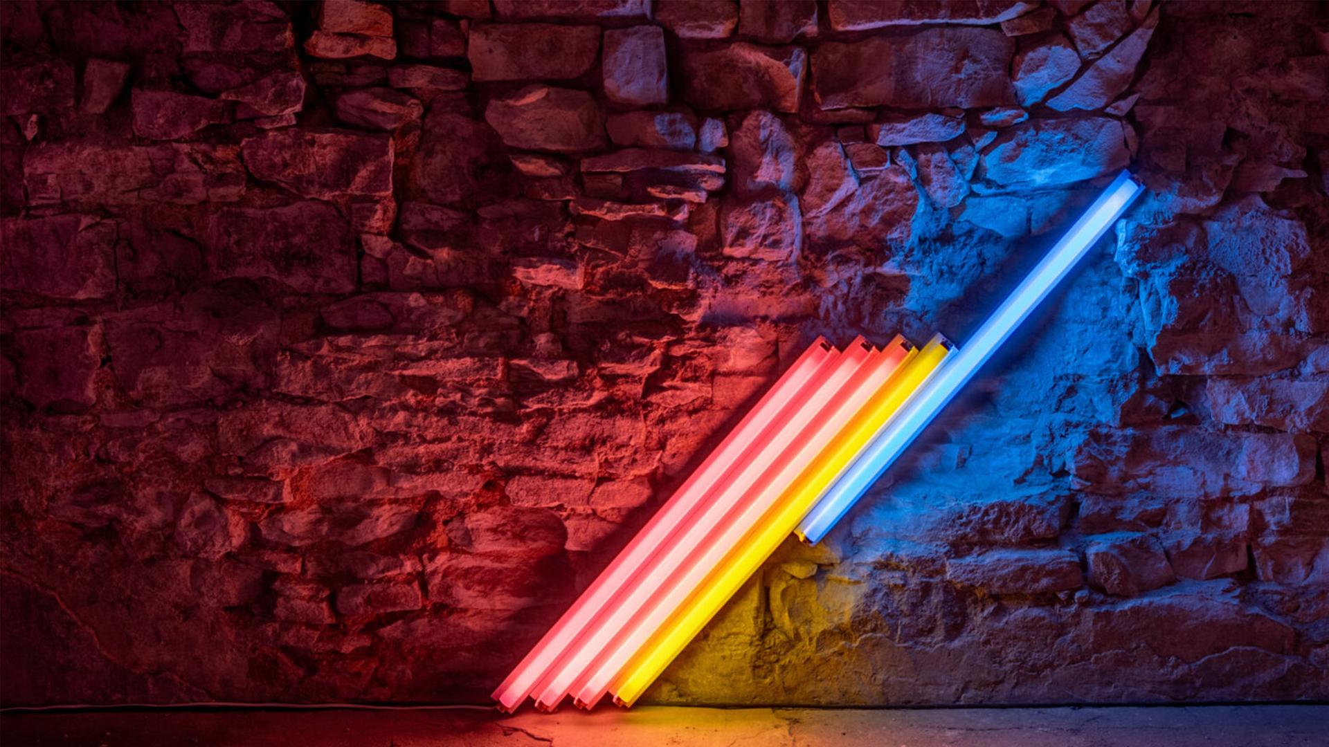 In einem abgedunkelten Ausstellungsraum sieht man eine Installation aus bunten, schräg nebeneinander angeordneten Neonröhren.