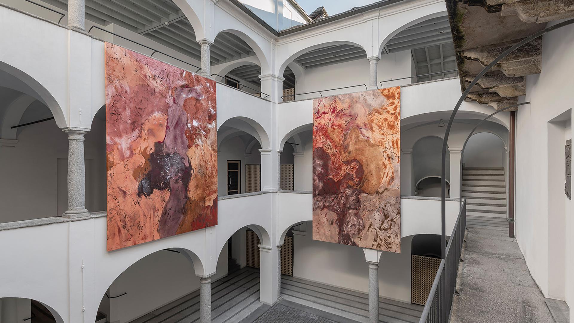 In einem Innenhof hängen zwei moderne Gemälde.