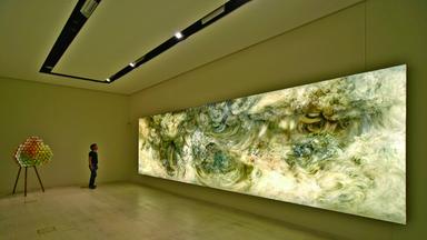 In einem Ausstellungsraum sieht man ein modernes Gemälde, das an Wellen und Wolken erinnert.