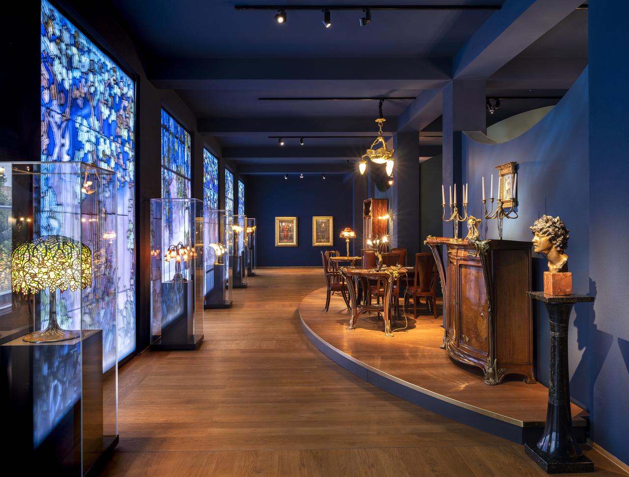 Ein blau gestrichener Raum mit Jugendstil-Möbeln und bunten Glasfenstern