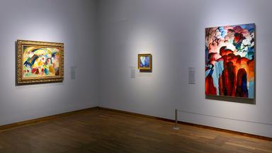 In einem Ausstellungsraum hängen moderne Gemälde an der Wand.
