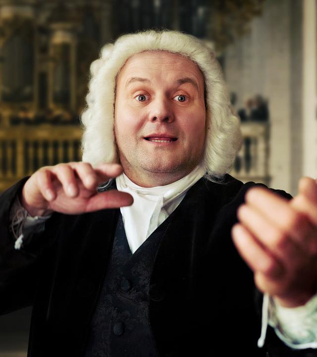 Ein Mann in Perücke dirigiert in einer Kirche.