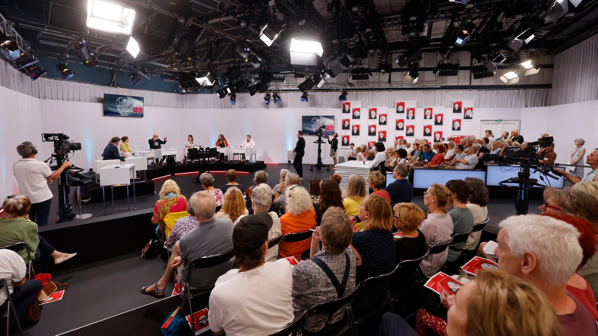 Blick ins vollbesetzte ORF-Studio während einer Jury-Sitzung der Tage der deutschsprachigen Literatur  mit Kamerateams, Publikum und großflächiger Porträtgalerie im Hintergrund.
