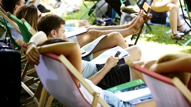 Lesende Menschen auf Sonnenstühlen im Freien