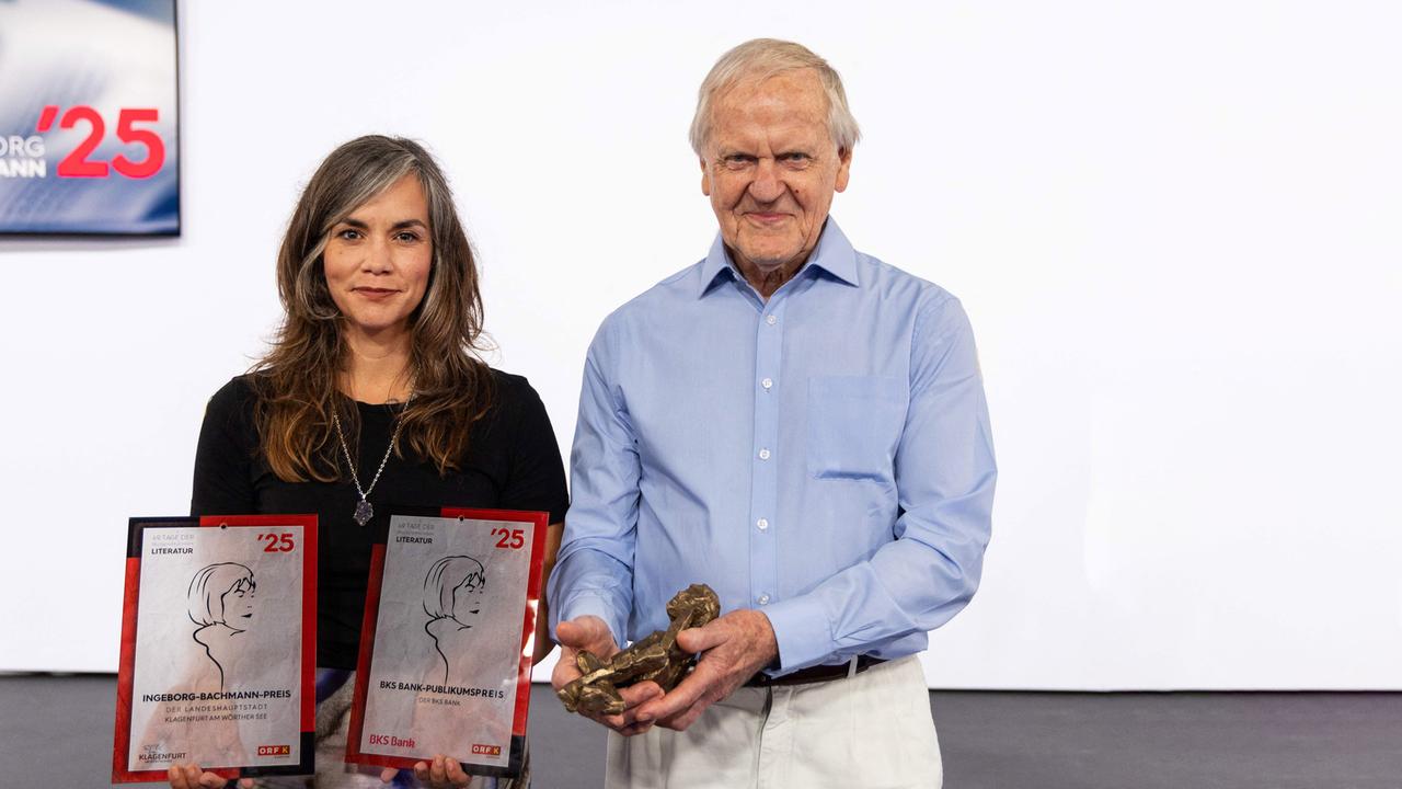 Eine Frau hält zwei Mappen mit Zertifikaten vor sich. Neben ihr steht ein Mann.