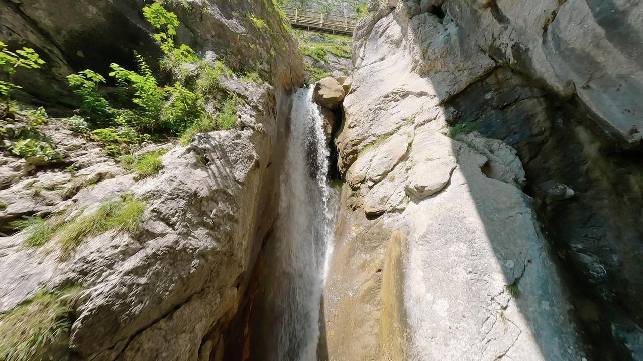 Felsenklamm mit Wasserläufen und hölzernen Stegen inmitten steiler Felswände