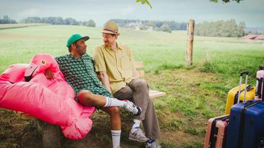 Von links: Simon Pearce und Sebastian Winkler auf einer Sitzbank im Urlaubsmodus.