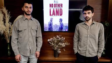 Zwei Männer stehen vor einem Filmplakat mit der Aufschrift "No Other Land"