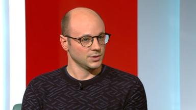 Junger Mann mit Glatze und Brille spricht in die Kamera.