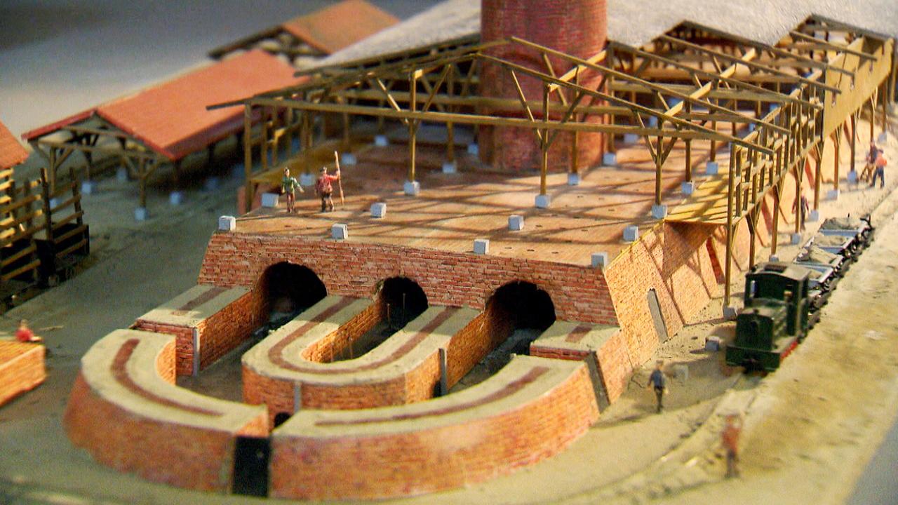 Aus kleinen Steinen und Holz mit kleiner Eisenbahn und kleinen Arbeitern