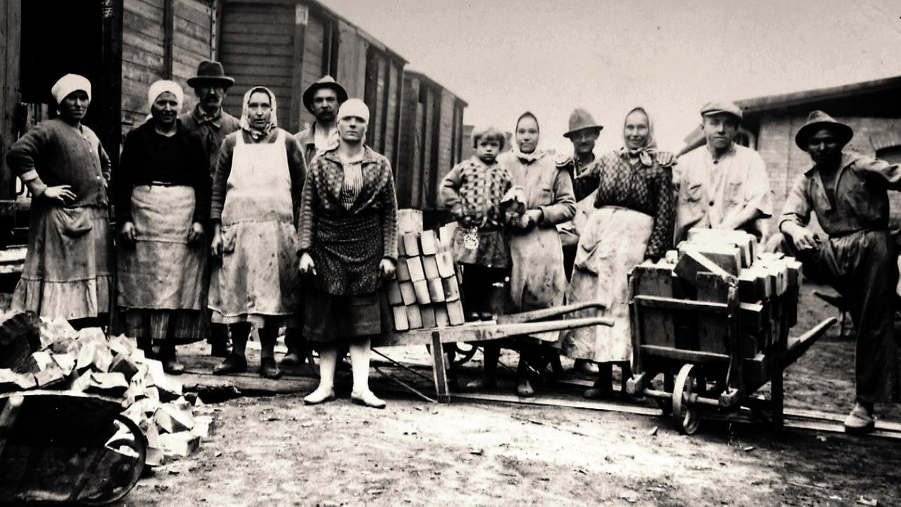 Sechs Frauen, vier Männer und ein Kind mit Ziegelstein-Schubkarren auf einer alten Fotografie