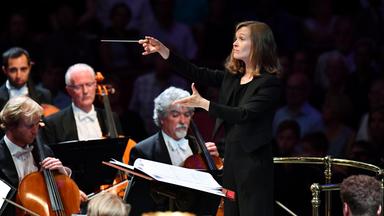 Das City of Birmingham Symphony Orchestra auf der Konzertbühne während des Konzerts. Die litauische Dirigentin Mirga Grazinyté-Tyla hält in der rechten Hand den Taktstock und dirigiert dynamisch, mit ausdruckstarkem Gesicht.